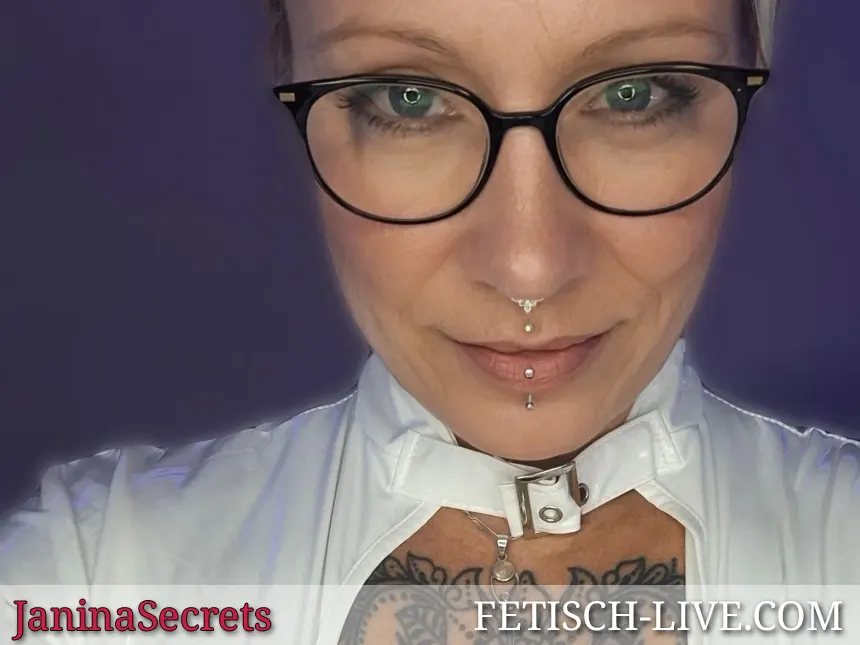 Herrin Janina Secrets mit Brille, Brust-Tattoo und Mund- Nasenpiercings schaut streng
